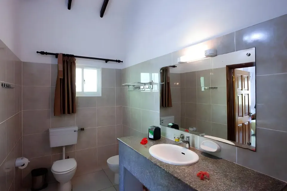 Badezimmer mit Steinplatte, großem Spiegel und Fenster