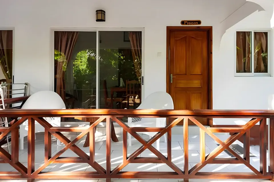 Terrasse einer Villa mit Holzgeländer, Glasschiebetür und einer Holztür mit Namensschild