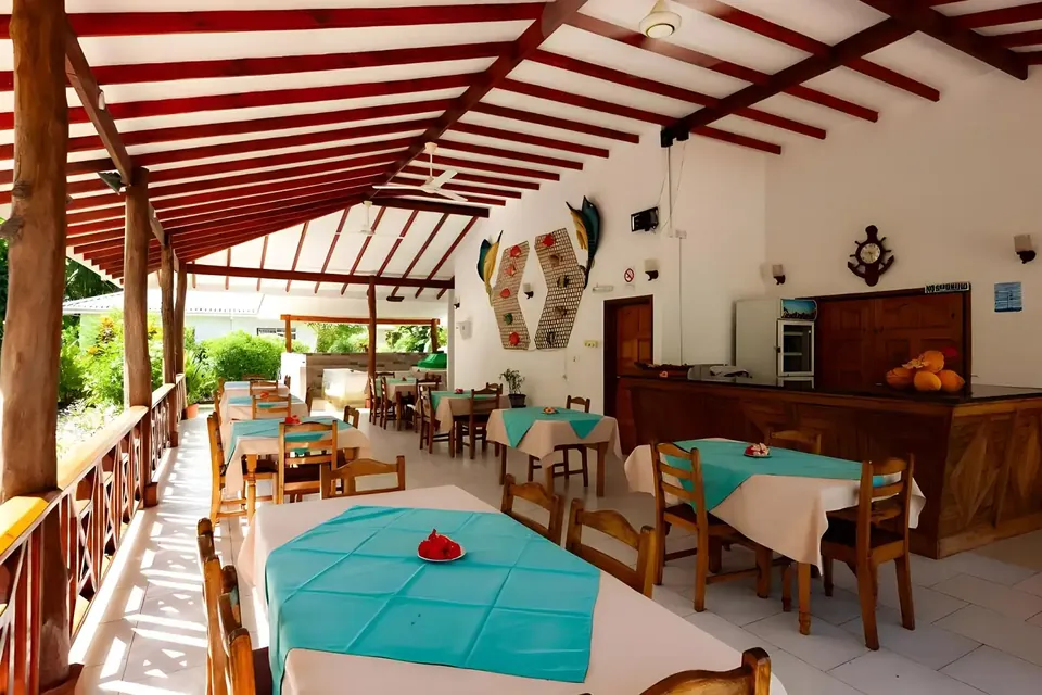 Das offene Restaurant mit türkisen Tischdecken, Holztresen und überdachter Veranda