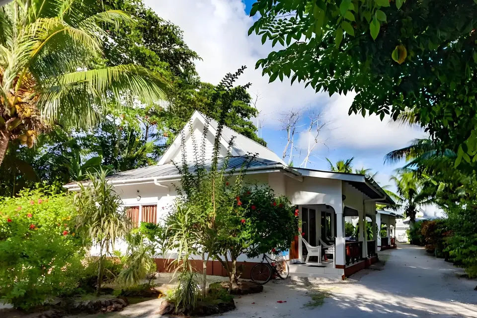 Eine Villa mit Spitzdach und schattiger Veranda, umgeben von blühenden Sträuchern